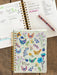 Notebook with floral and chicken design on cover, open to a page with handwritten notes.