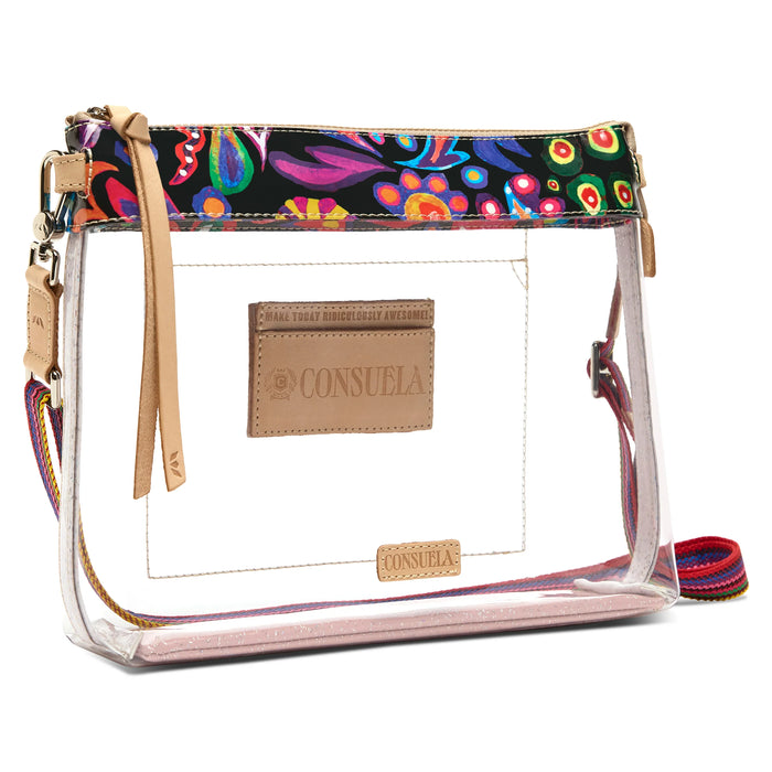 A clear plastic zippered pouch bag with a colorful paisley patterned top trim, tan leather brand patches, and a multicolor woven shoulder strap on a white background.