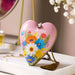 Heart-shaped pink decorative item with floral design and 'Love You Mom' text on a table.