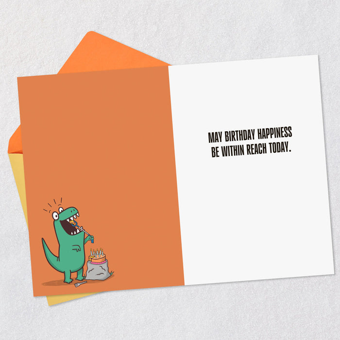 Birthday card with a green dinosaur illustration and humorous text on an orange envelope.
