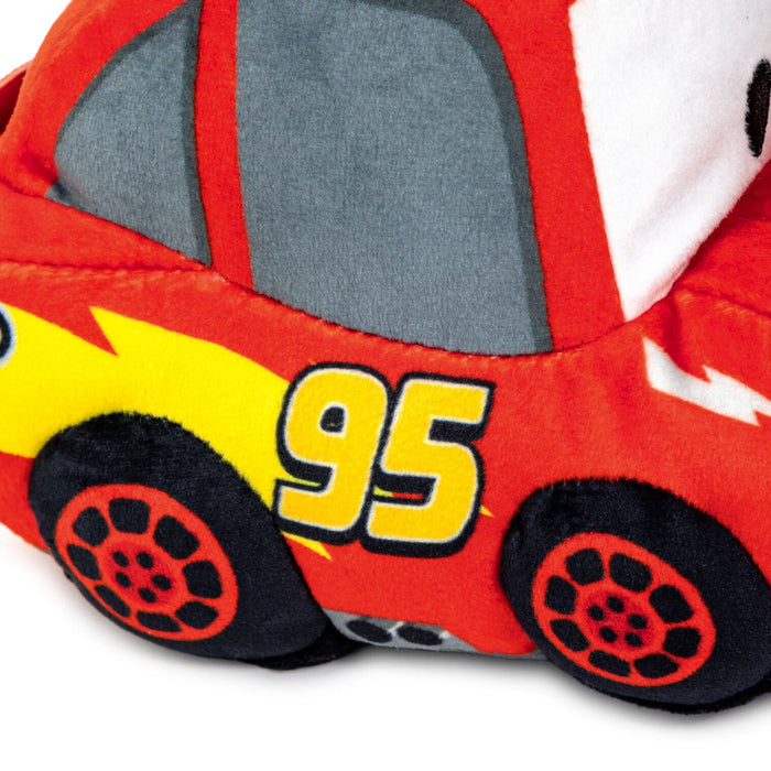 A close-up of a plush toy car inspired by Lightning McQueen, featuring red fabric body panels, gray windows, a yellow lightning accent, the number 95 in yellow, and black wheels.