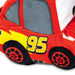 A close-up of a plush toy car inspired by Lightning McQueen, featuring red fabric body panels, gray windows, a yellow lightning accent, the number 95 in yellow, and black wheels.