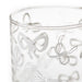 A close-up of a clear glass tumbler featuring a frosted etched pattern of delicate bows in light gray.