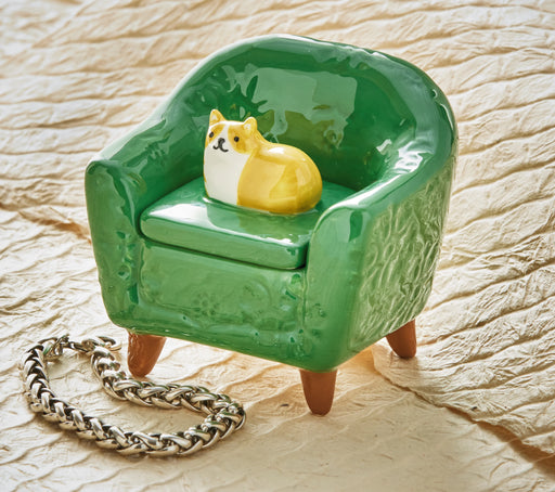 Green miniature armchair with a small dog figurine on a textured surface