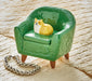 Green miniature armchair with a small dog figurine on a textured surface