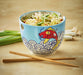 Blue bowl with noodles and a fish design on a wooden surface with chopsticks.