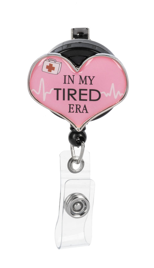 Heart-shaped badge holder with 'In My Tired Era' text on a white background