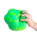 Hand holding a green and blue marbled stress ball against a white background