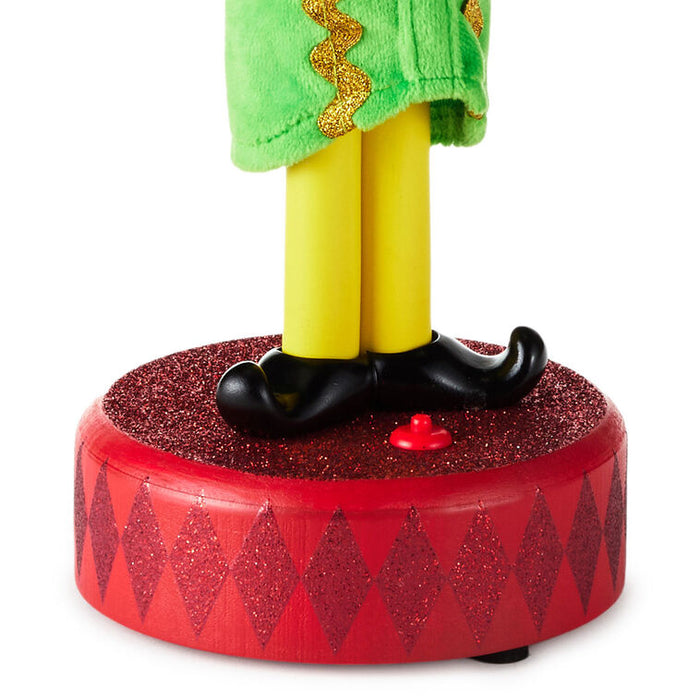 Toy figure with green top, yellow legs, black shoes, and red base on a white background