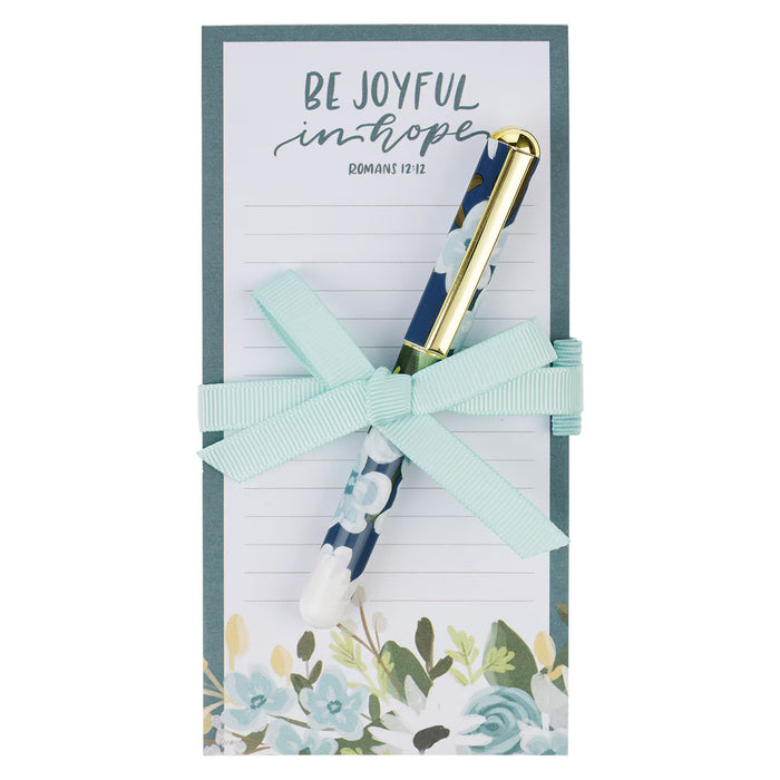 Notebook with floral design and pen set, tied with a ribbon, on a white background.