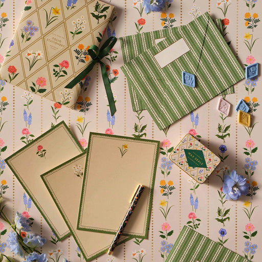 Stationery items including notebooks, envelopes, and cards on a floral-patterned surface.