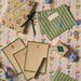 Stationery items including notebooks, envelopes, and cards on a floral-patterned surface.