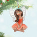 Fairy ornament with white wings and an orange dress on a light blue background