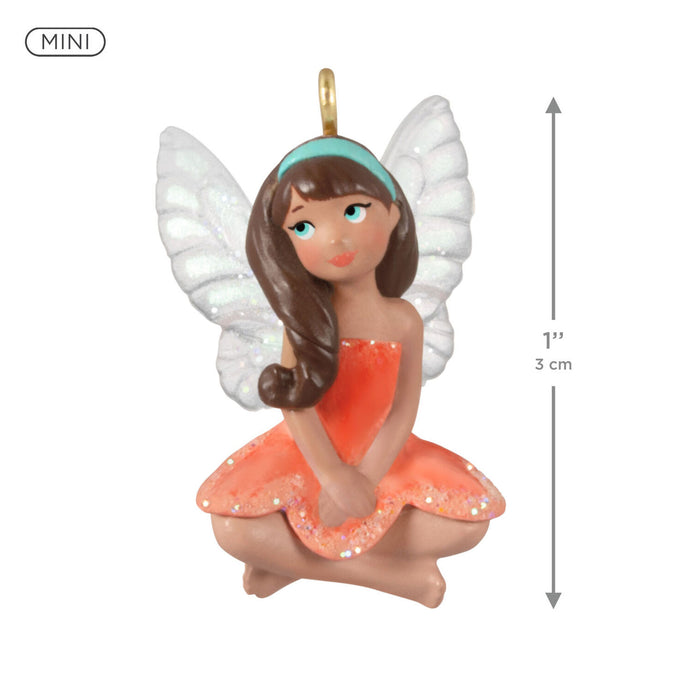 Miniature fairy figurine with white wings and an orange dress, shown with a measurement indicator.