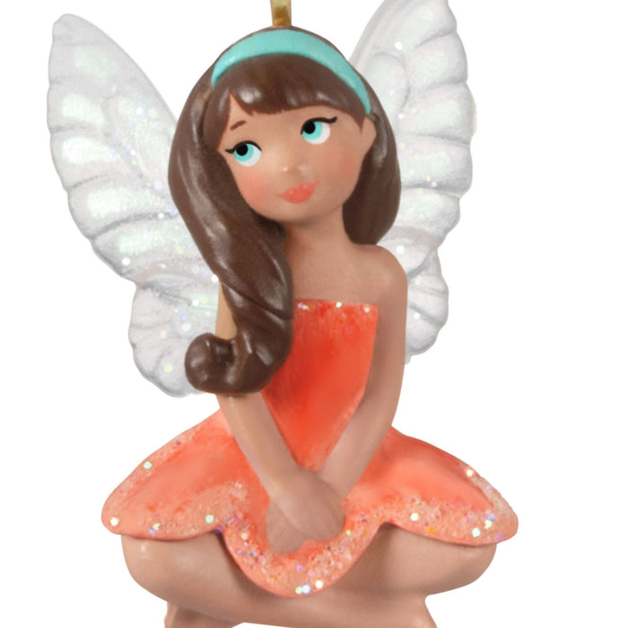 Fairy figurine with white wings and an orange dress on a white background