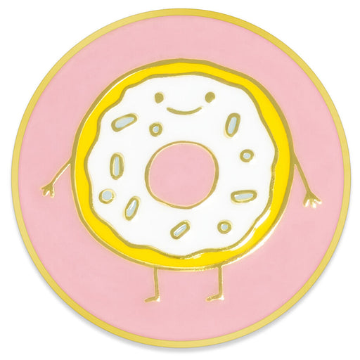 A circular enamel pin or sticker featuring a cute, smiling cartoon donut with white frosting, gold outlines, and small legs and arms, set against a pink background with a gold outer border.