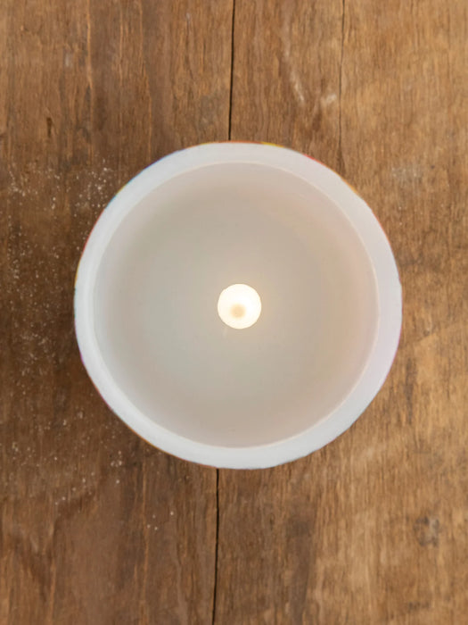 White ceramic bowl with a candle on a wooden surface