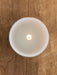 White ceramic bowl with a candle on a wooden surface