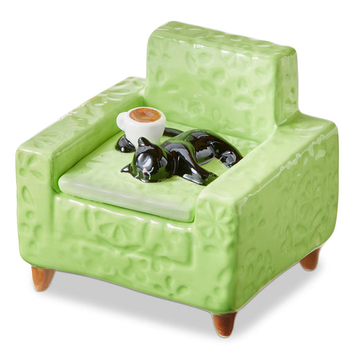 Green ceramic armchair with a small table and decorative items on a white background