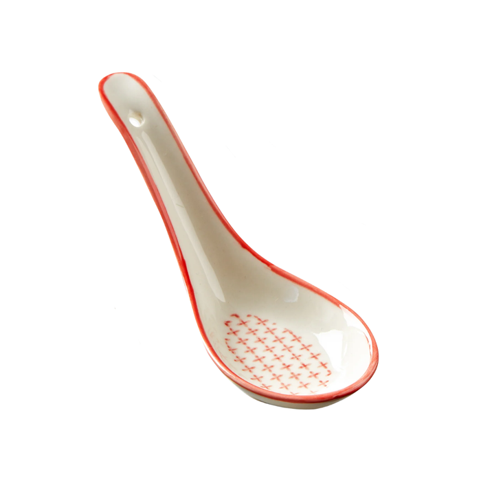 White ceramic spoon with red rim and pattern on a white background
