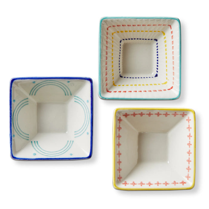Three square ceramic bowls with colorful decorative edges on a white background