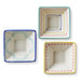 Three square ceramic bowls with colorful decorative edges on a white background