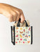 Hand holding a small bag with colorful patterns on a white background