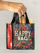 Hand holding a floral 'Happy Bag' with groceries against a neutral background