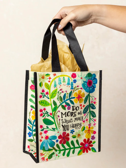 Colorful tote bag with floral design and text held by a hand against a beige background