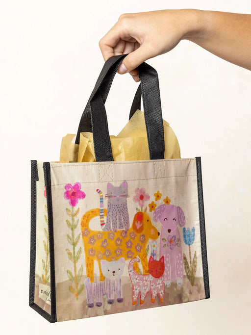 Hand holding a colorful tote bag with animal illustrations on a white background