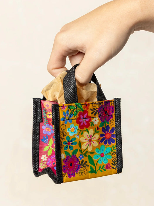 Colorful floral-patterned bag held by a hand against a beige background