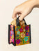 Colorful floral-patterned bag held by a hand against a beige background