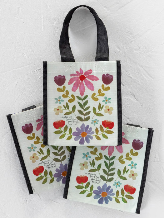 Set of three floral tote bags with black handles on a light gray background