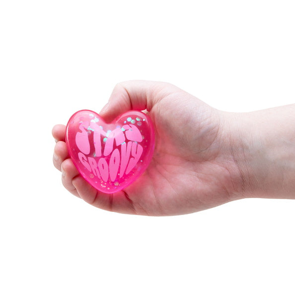 Hand holding a pink heart-shaped object with 'Stay Groovy' text on a white background