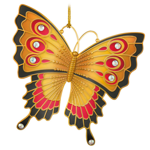 Decorative butterfly ornament with gold, red, and black colors on a white background