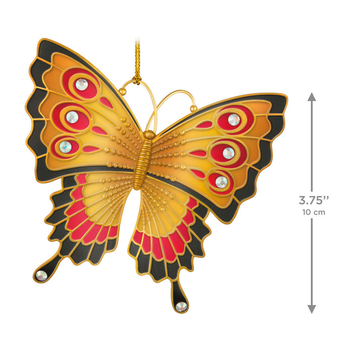 Butterfly-shaped ornament with gold, red, and black colors on a white background
