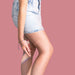Person wearing denim shorts on a pink background