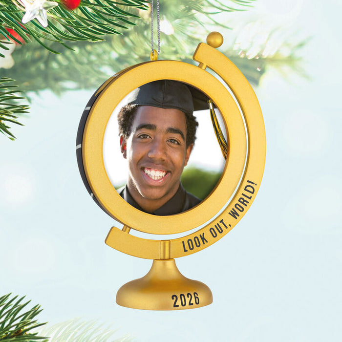 Gold graduation-themed ornament with a photo of a person and 'Look Out, World! 2026' text, hanging on a Christmas tree.