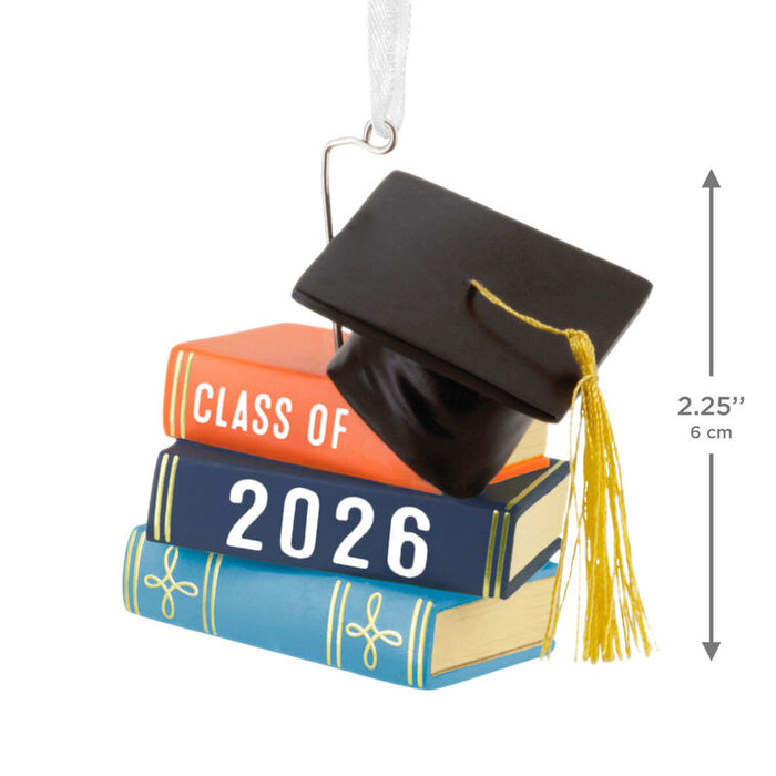 Graduation-themed ornament with books and cap, labeled 'Class of 2026', on a white background.
