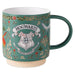 A teal ceramic mug featuring the Hogwarts crest and floral illustrations, with a dark green handle and interior, set against a plain white background.