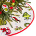 Christmas tree skirt with Grinch design around a decorated Christmas tree.