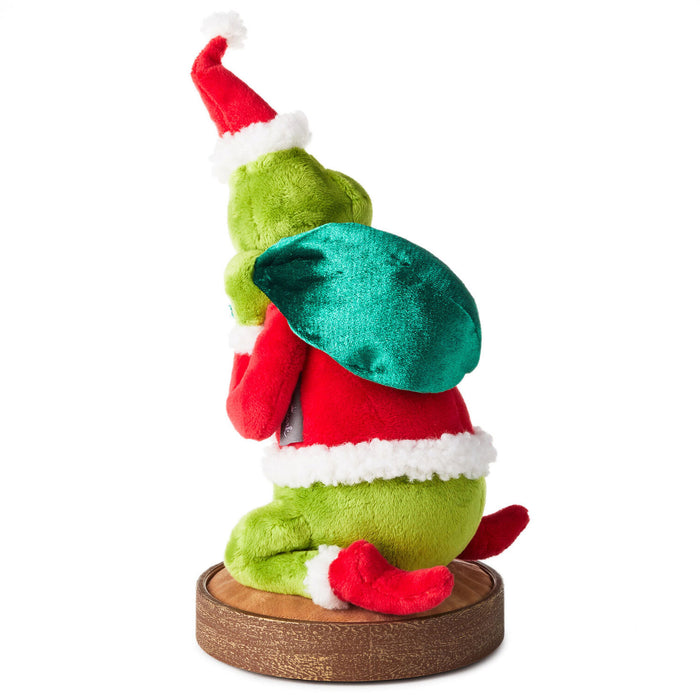 Green elf plush toy with red hat and shoes on a white background