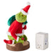Plush toy resembling a character in a Santa outfit with a white wall outlet on a white background