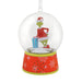 A Grinch-themed snow globe ornament featuring a green Grinch figure in a red Santa outfit holding blue presents inside a clear globe, mounted on a red patterned base with white snowflakes.