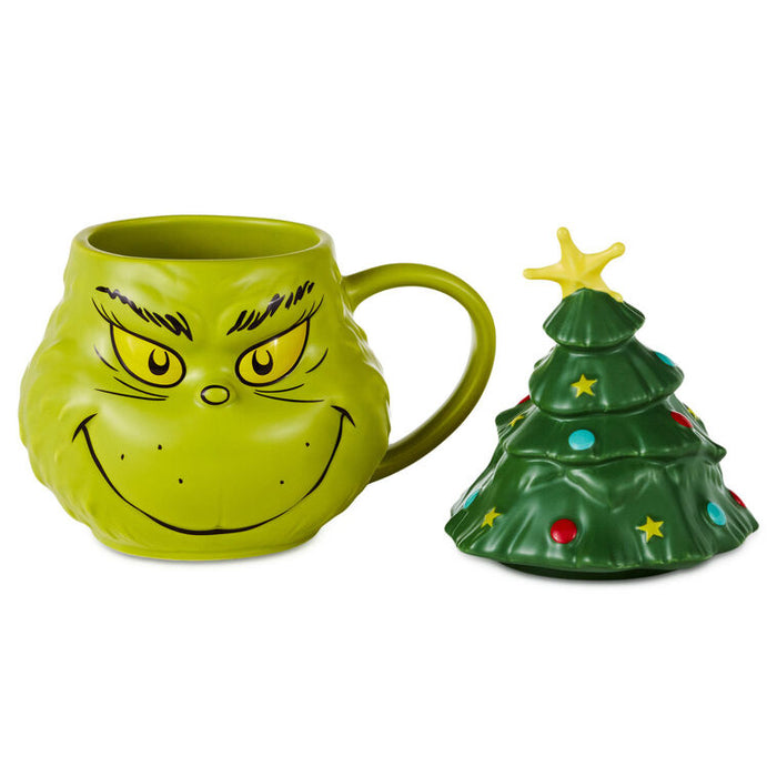 A green Grinch-themed ceramic mug with a handle, shown next to a matching Christmas tree-shaped lid on a plain white background.