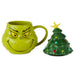 A green Grinch-themed ceramic mug with a handle, shown next to a matching Christmas tree-shaped lid on a plain white background.