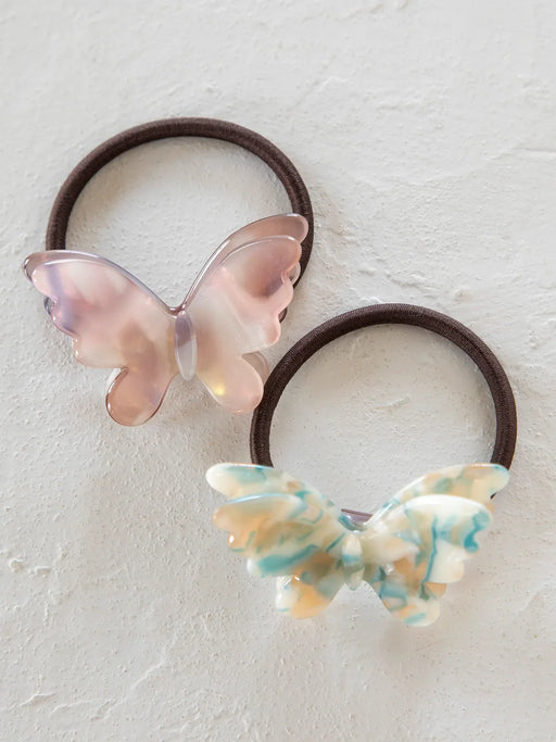 Two butterfly-shaped hair ties on a light background