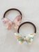 Two butterfly-shaped hair ties on a light background