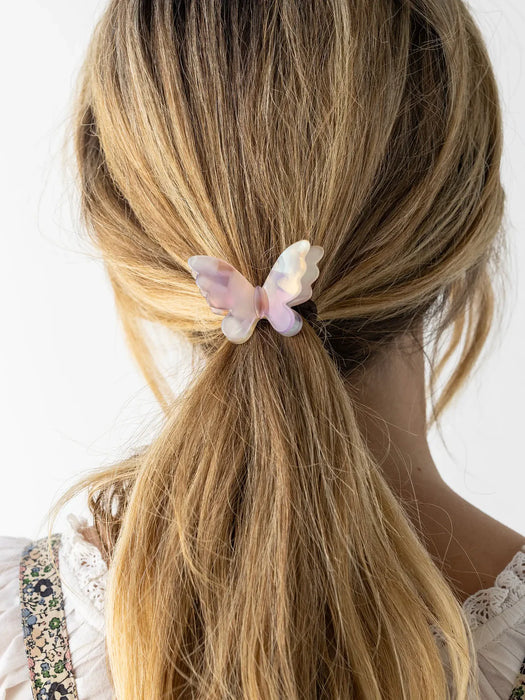 Butterfly-shaped hair clip in a person's blonde hair against a white background