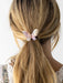 Butterfly-shaped hair clip in a person's blonde hair against a white background